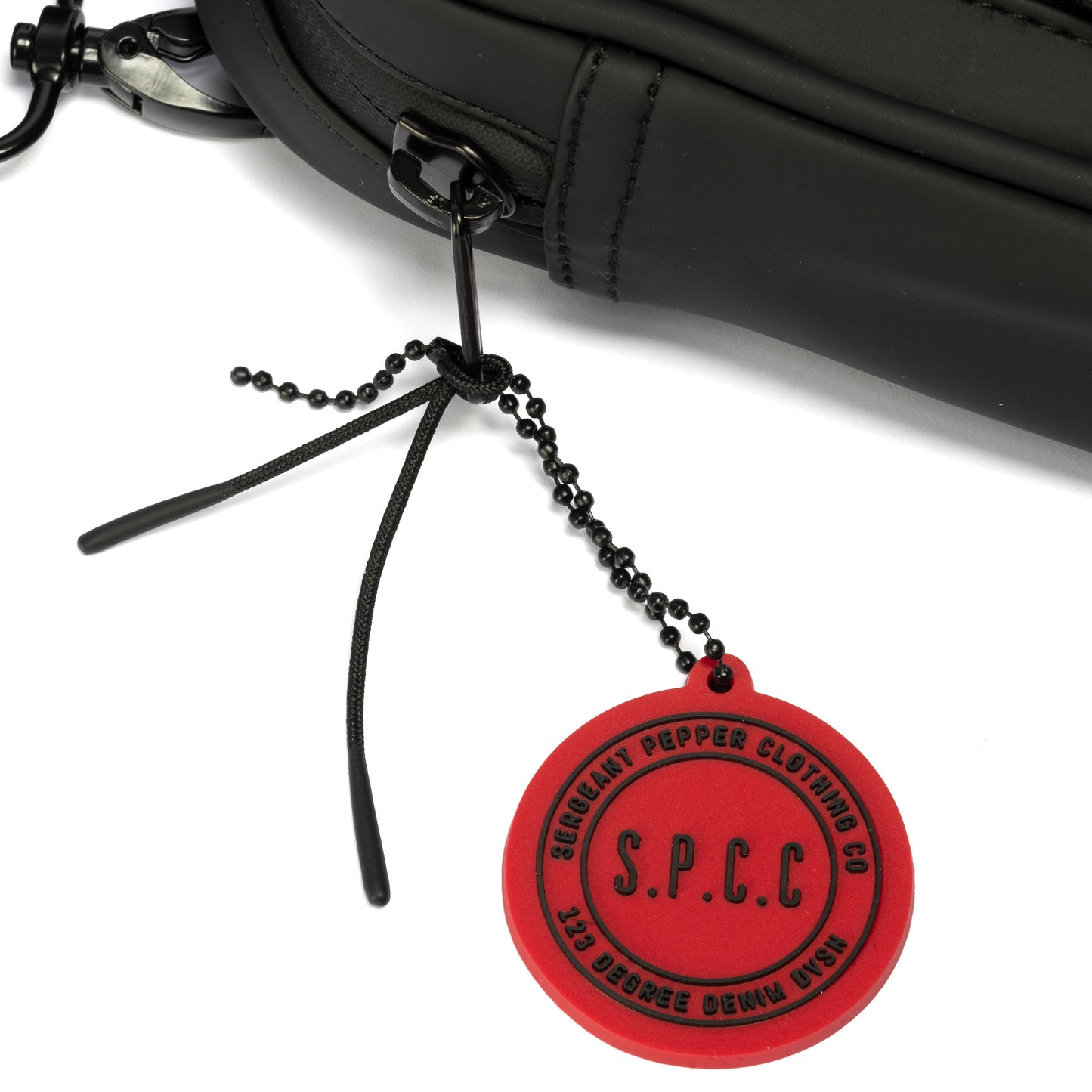 Surge Atlas Hip Bag - Black close-up of red SPCC tag and black hardware detail.